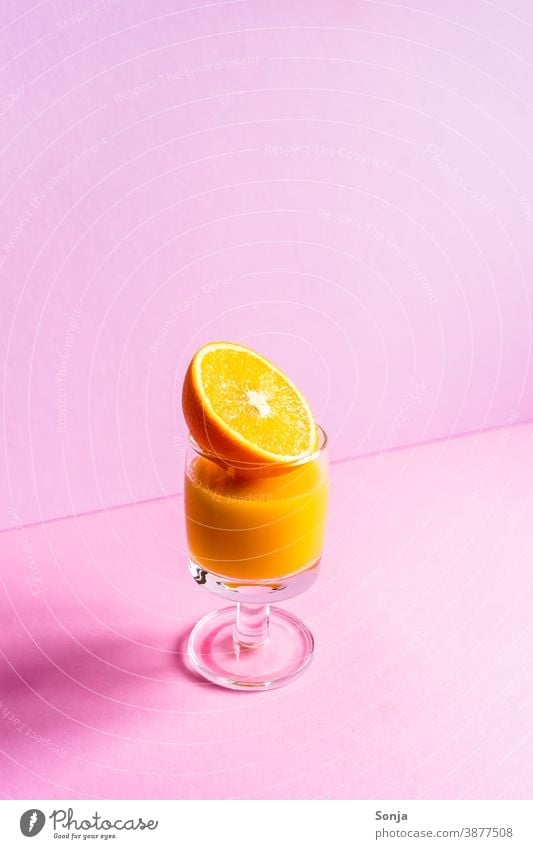 A glass of orange juice with a halved orange on an isolated pink background Orange juice Glass Beverage Citrus fruits Juice Fresh segregated Refreshment