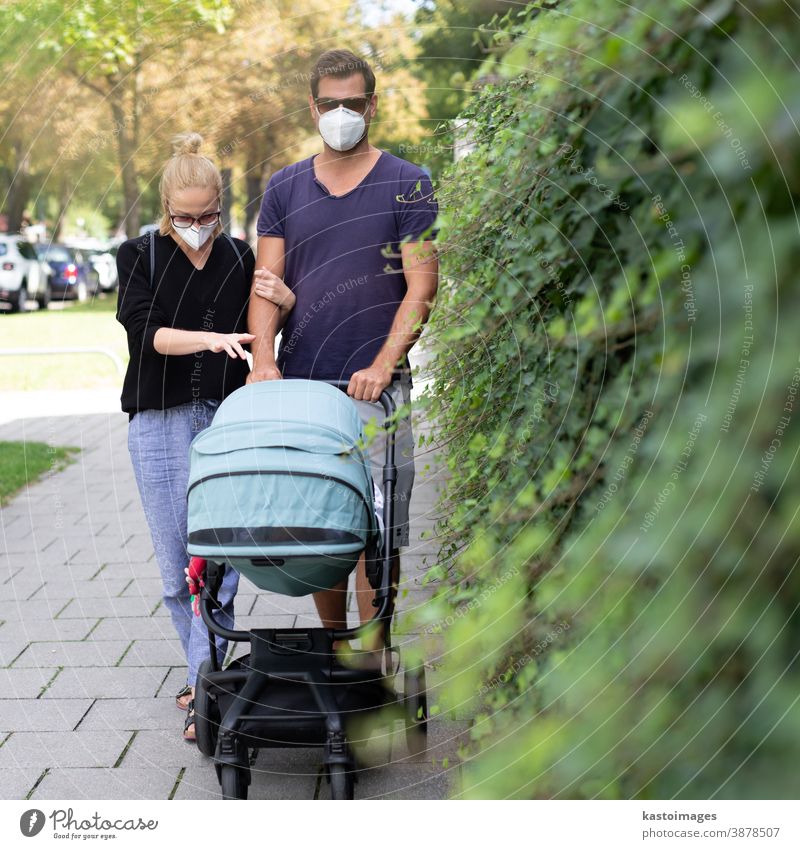 Worried young parent walking on empty street with stroller wearing medical masks to protect them from corona virus. Social distancing life during corona virus pandemic