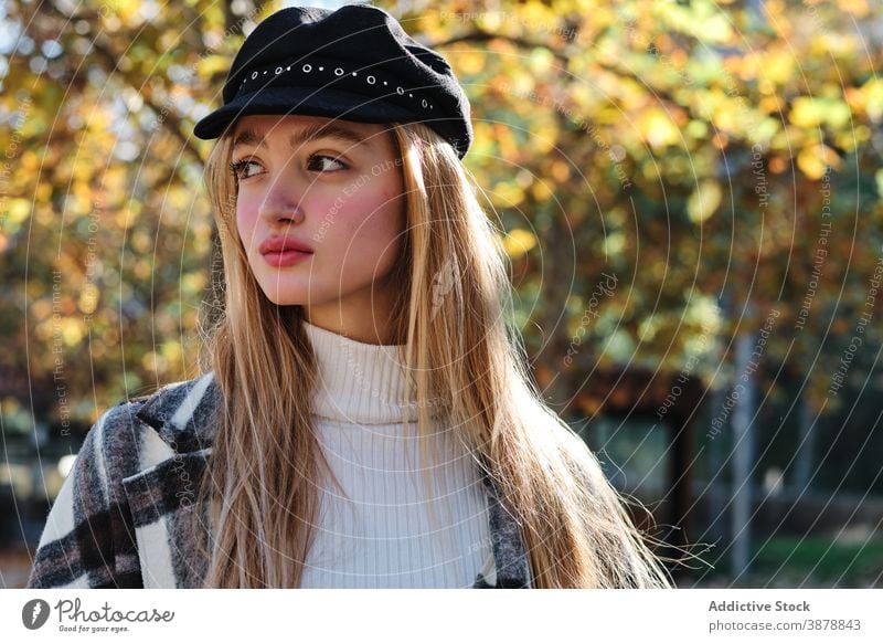 Relaxed woman in trendy outfit and hat in autumn park fashion style checkered relax fall season young female blond millennial teenage enjoy tranquil calm rest