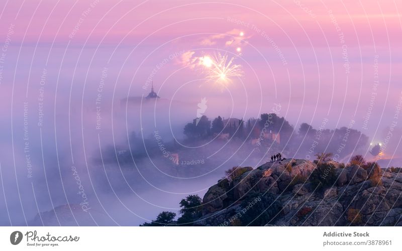 People watching fireworks from the rock in medieval city in fog in sunrise people stand ancient town palace mist daybreak landscape colorful old architecture