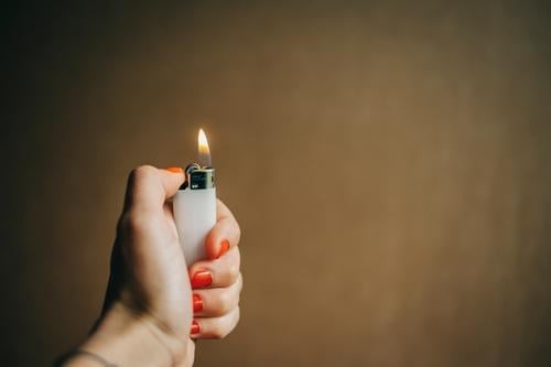 A female hand holds a burning lighter Lighter Burn Ignite Rousing Fire Flame Hand Hot Nail polish Kindle feminine Women`s hand Neutral Background Warmth