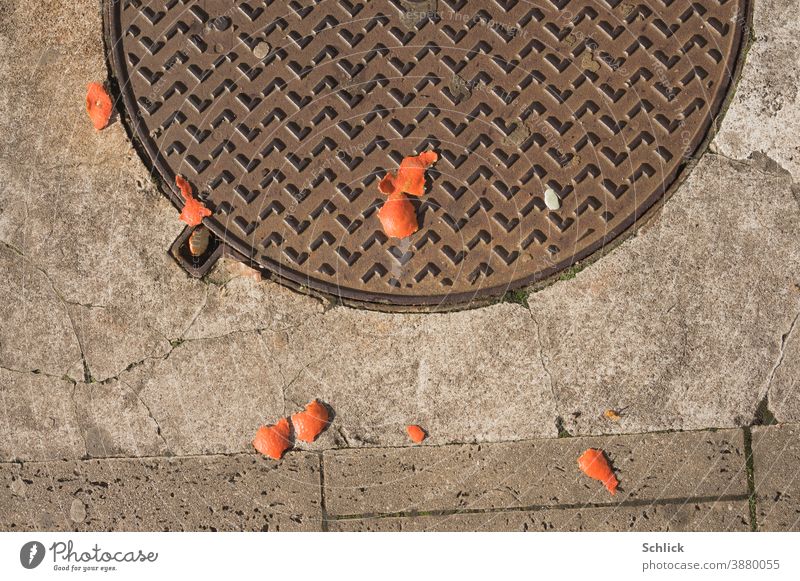 Disposable society christmas background of discarded mandarin peels and manhole covers Christmas Tangerine shells Orange peel pieces jettisoned Concrete Stone