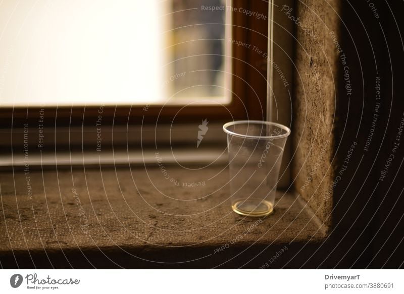 Abandoned empty plastic cup on a window sill glass waste litter littering thirsty copy space background drink transparent party recycle closeup blur nobody