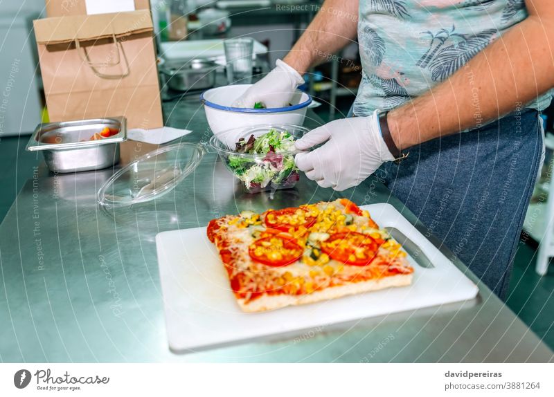 Unrecognizable cook preparing takeaway orders unrecognizable packing salad gloves hygiene safe food industrial kitchen package take away pizza focaccia