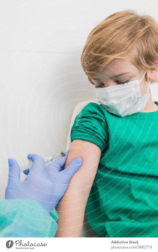 Doctor giving injection for kid in mask in hospital vaccine coronavirus syringe doctor child prevent covid 19 sterile health care medical professional