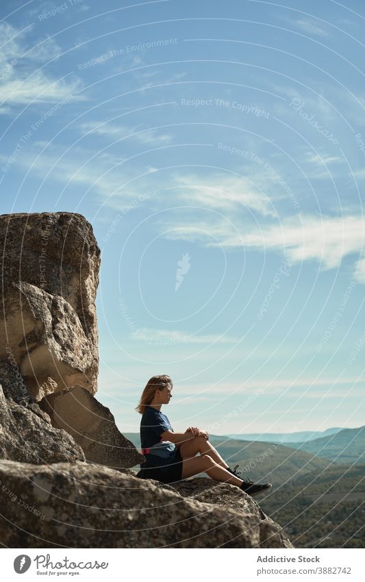Traveling woman sitting on rock in highlands hiker mountain trekking viewpoint relax freedom enjoy hill female rocky adventure majestic scenery tourism summer