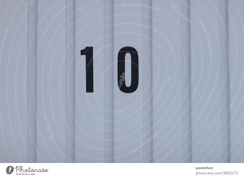 Ten, full score. Black number ten on a garage door. Numbering, assignment. mark Garage Garage door Closed classification Highway ramp (entrance) Gloomy