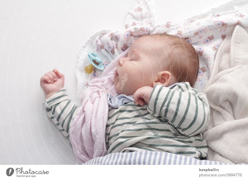 Baby sleeps on a bed with blankets Toddler Bed Soother Rag Blanket Sleep Siesta Peaceful Calm Dream Face