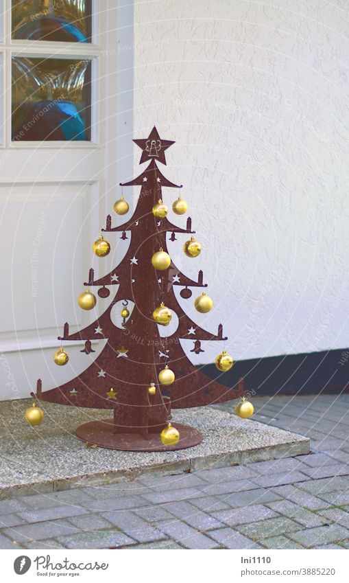Christmas tree made of rusty metal and decorated with golden baubles stands in front of the white entrance Christmas decoration meltall gold balls standing Feet