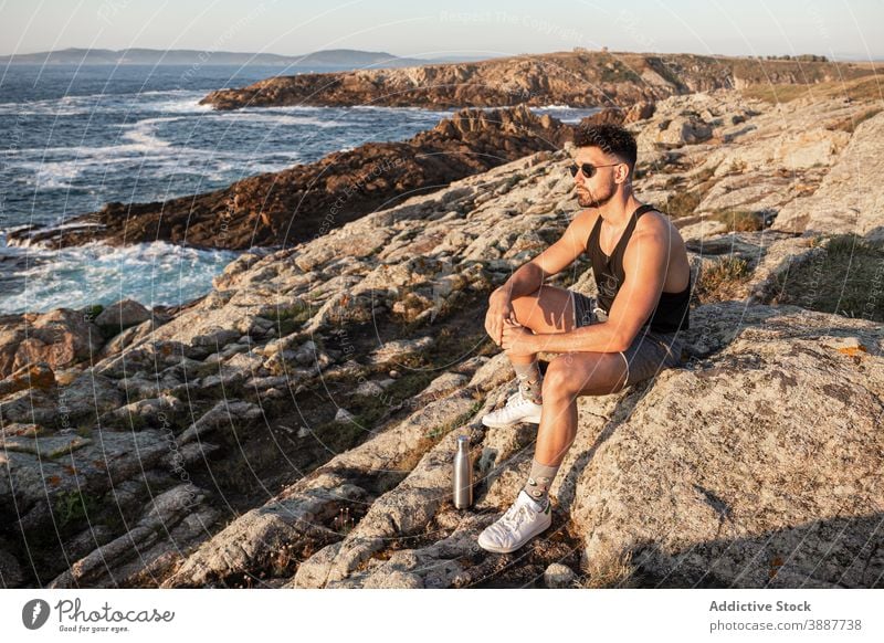 Tranquil man enjoying seascape in summer at sunset admire peaceful harmony sundown relax male rock coast calm beach shore nature sit water rest seaside freedom
