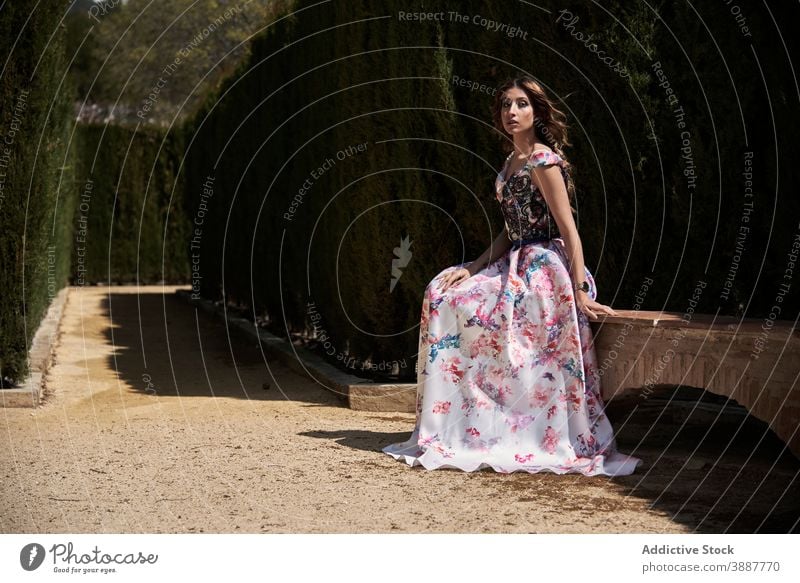 Young woman in long stylish dress in park elegant maxi grace long dress style charming garden bench alley relax sit stone gorgeous calm chic summer trendy young
