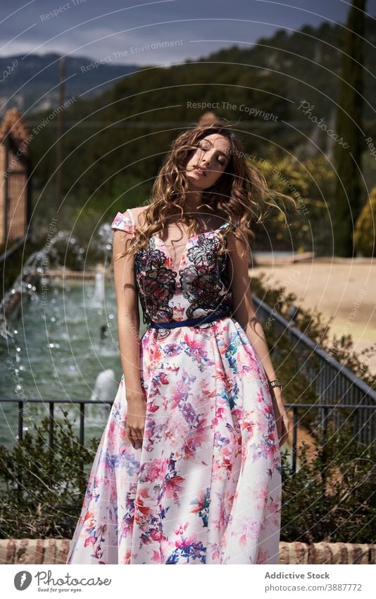 Graceful woman in long dress in park grace maxi elegant charming appearance beauty tender style chic relax young garden wavy hair trendy fountain long hair