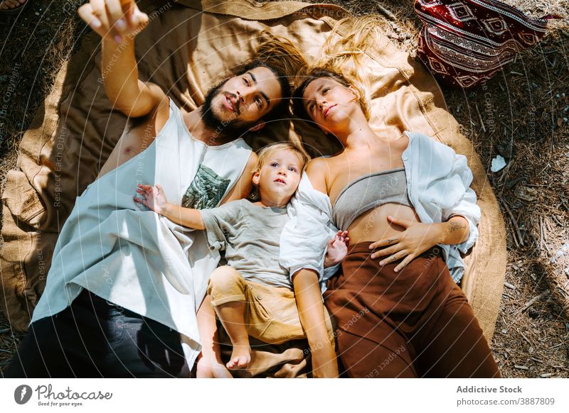 Carefree family resting on blanket in nature dreamy daydream carefree forest hipster hippie unity relax freedom multiethnic multiracial diverse lying little kid