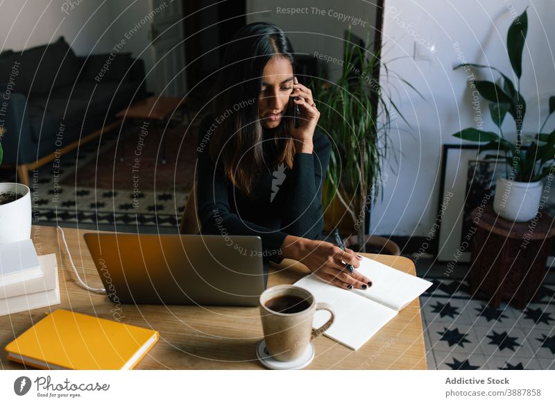 Indian woman talking on smartphone at home startup freelance project speak remote work female ethnic indian office cellphone entrepreneur table gadget