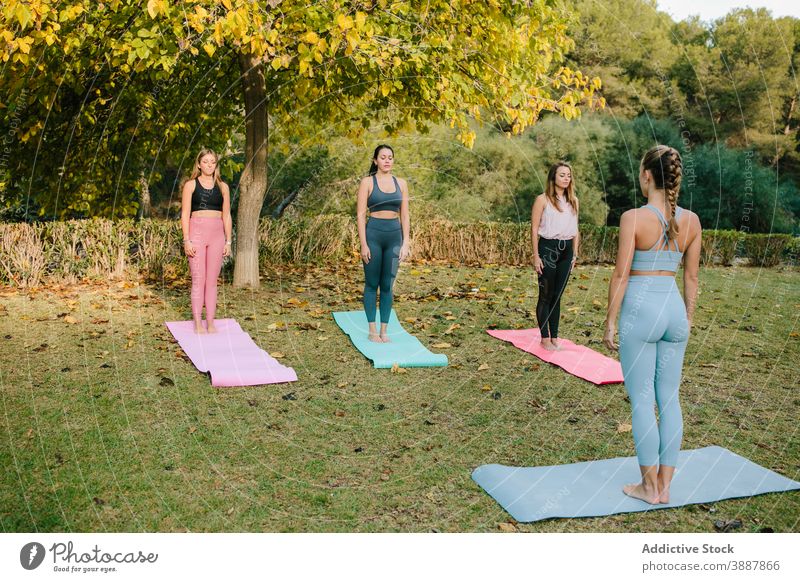 Young women with instructor practicing yoga in park group practice mountain tadasana pose young together female wellness harmony vitality nature lifestyle