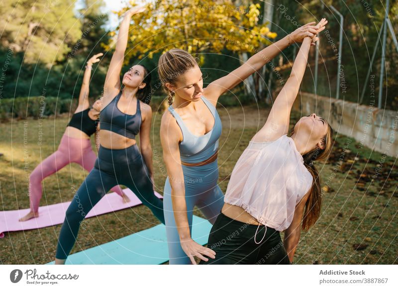 Instructor helping woman during yoga practice in park instructor women exalted crescent lunge asana pose group female wellness lifestyle harmony wellbeing zen
