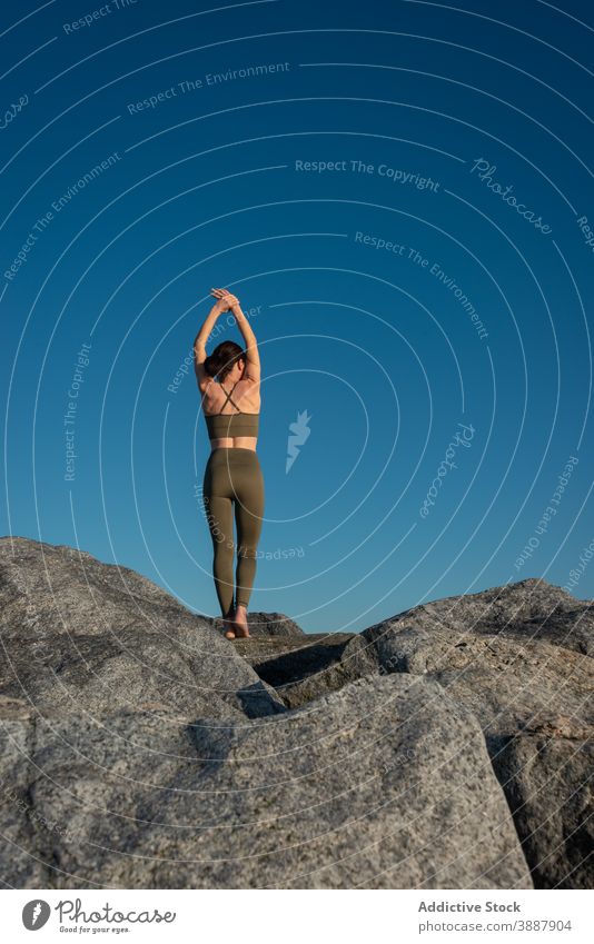 Anonymous focused woman practicing yoga on rock relax stone blue sky nature mindfulness zen female practice wellness harmony wellbeing calm lifestyle vitality