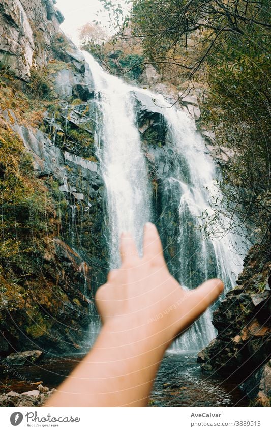 Out of focus hand reaching to a majestic waterfall nature tree western serene scenery natural peaceful foliage landscape cascade forest national mountain park