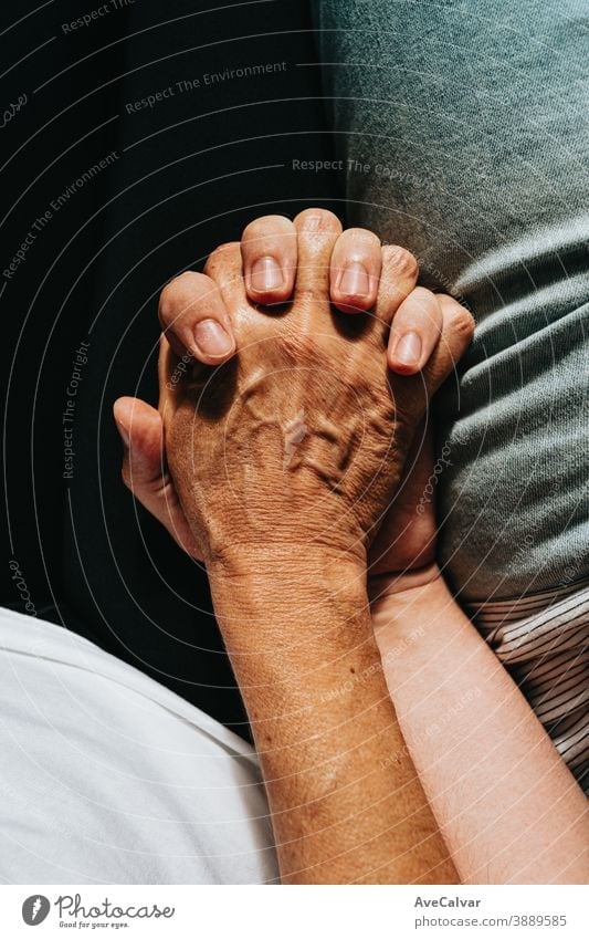 Close up of an old hand grabbing a young hand on cinematic tones assistance community females friendship grandparent holding hands horizontal reaching touching