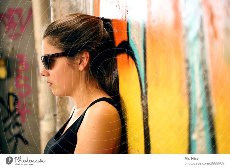 Teen leans relaxed against a graffiti wall Graffiti Wall (building) Wall (barrier) Girl Sunglasses portrait Hair and hairstyles Looking Authentic Orange