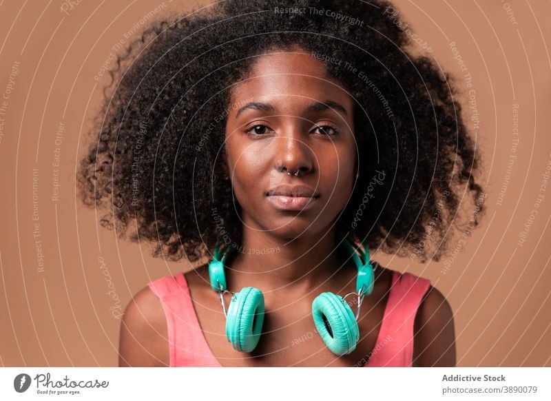 Ethnic woman with headphones standing in studio fun music style colorful hairstyle afro ethnic cuban african american black smile trendy dress carefree listen
