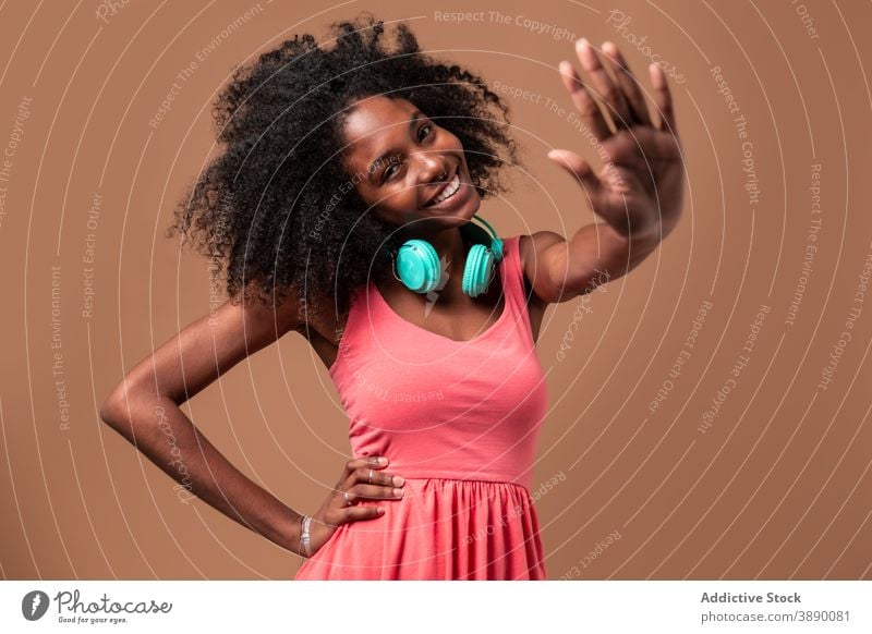 Ethnic woman with headphones standing in studio dance fun music happy style colorful hairstyle afro ethnic cuban african american black smile trendy dress