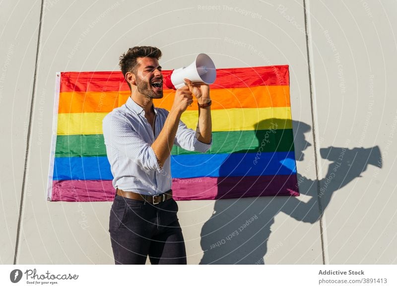 Gay man screaming in megaphone on street loudspeaker homosexual lgbt flag rainbow gay expressive male lgbtq pride tolerance cheerful city right equal yell
