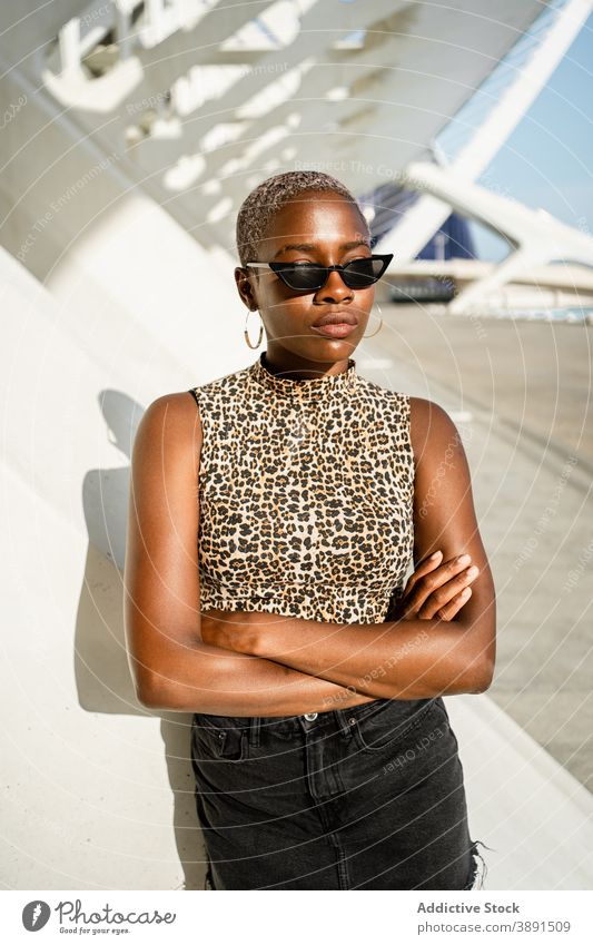 Serious black woman standing on street female ethnic african american cool sunglasses style urban young trendy expressive garment bright individuality braid