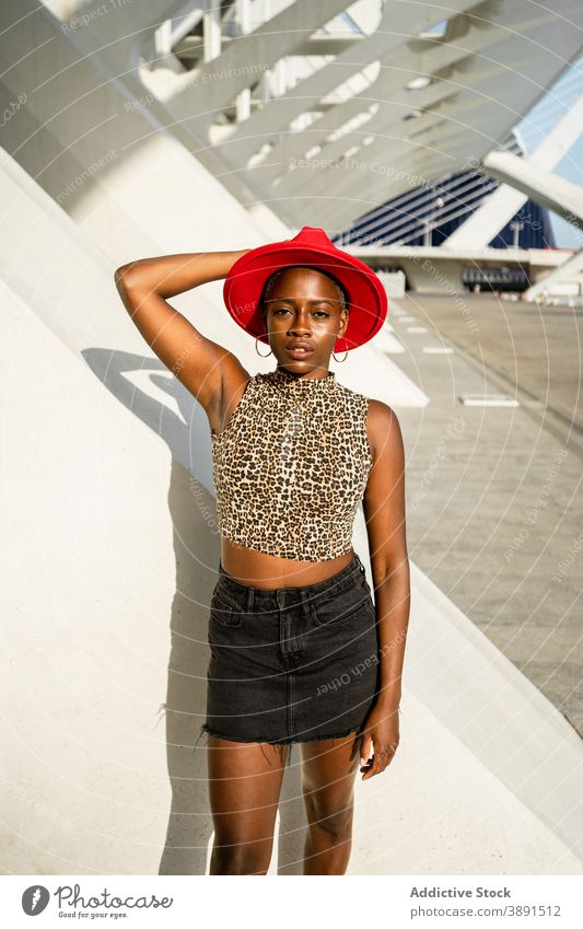 Stylish black woman in red hat in city style dreamy carefree urban trendy accessory female ethnic african american looking at camera sunny young summer outfit