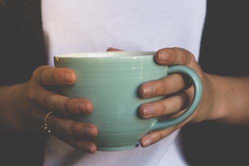 Close-up of a large light green cup of coffee or tea in the hands of a young woman. Cup Mug stop To hold on Coffee Tea Bright green Black White Beverage Tea cup