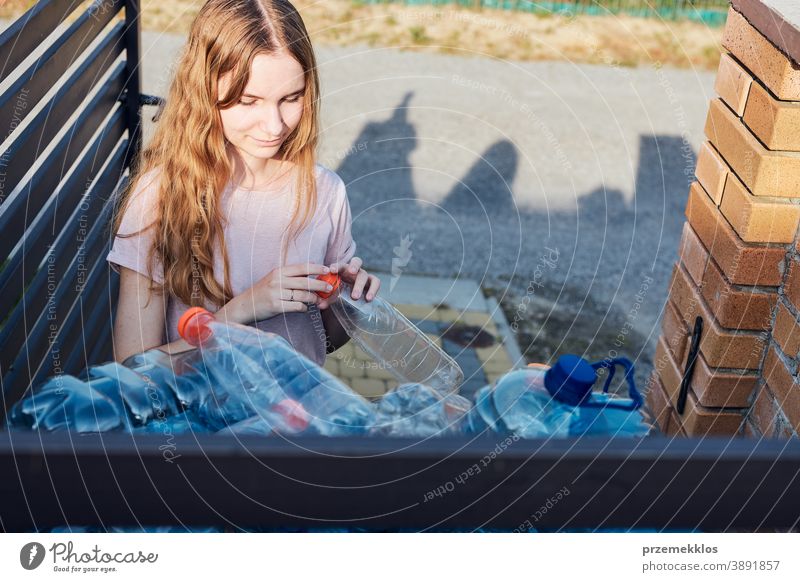 Young woman throwing out empty used plastic water bottles into trash bin blue collect collecting container crushed disposal ecology environment female garbage
