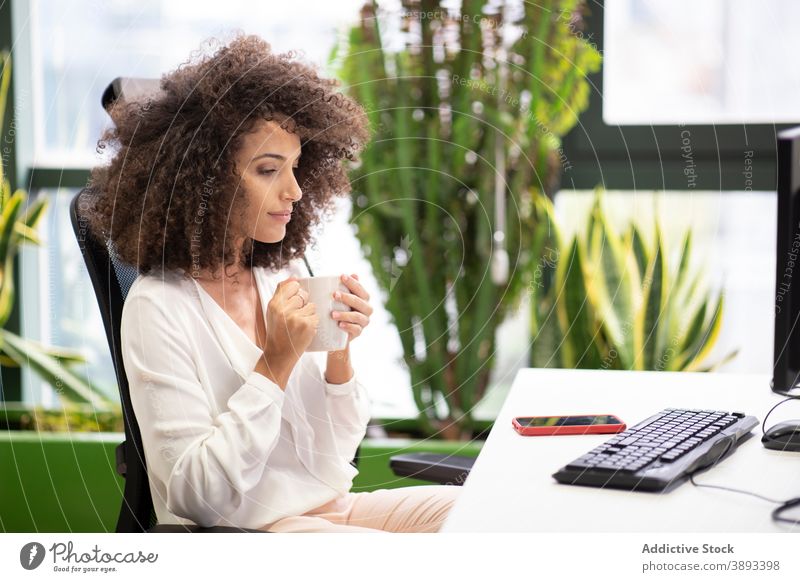 Businesswoman with cup of coffee working in office businesswoman computer drink think workplace busy young ethnic hispanic modern pensive thoughtful break rest