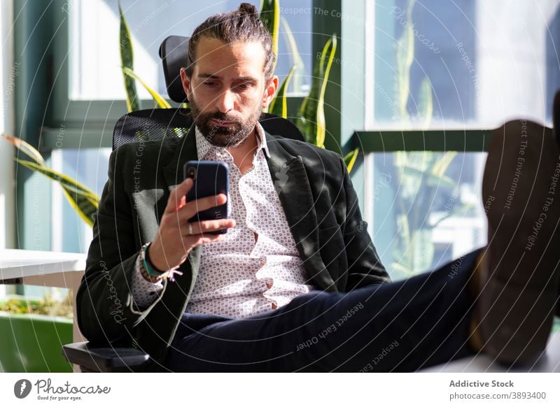 Serious businessman using smartphone in office read concentrate serious entrepreneur mobile break beard formal work workspace device gadget browsing connection