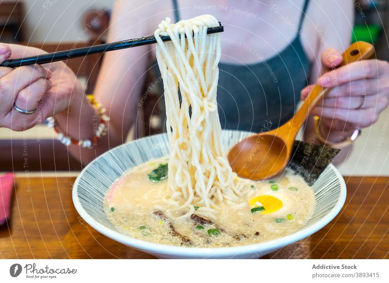 Crop woman eating Asian noodle soup in cafe asian food lunch egg oriental tradition female restaurant cuisine tasty table meal delicious chopstick bowl yummy