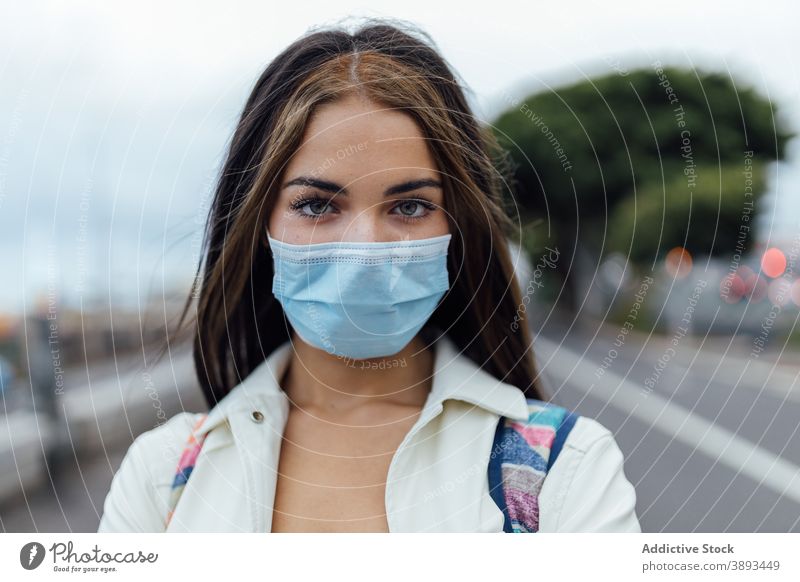 Young woman in medical mask on street coronavirus pandemic disposable serious young covid 19 epidemic covid19 millennial female prevent infection protect