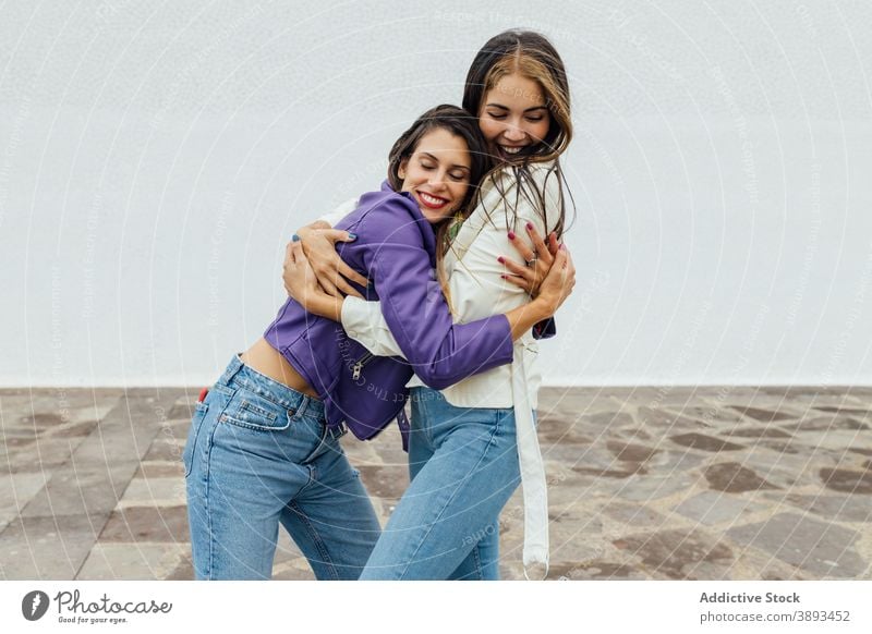 Happy girlfriends hugging on street embrace happy trendy young cheerful meeting urban together laugh female friendship relationship joy women glad optimist