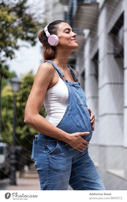 Carefree pregnant woman listening to music in city - a Royalty Free Stock  Photo from Photocase