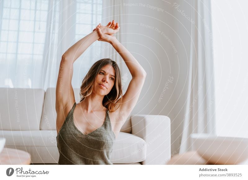 Calm woman stretching body in morning at home arm warm up tranquil enjoy tender serene female floor calm rest sit peaceful relax young quiet wellbeing idyllic