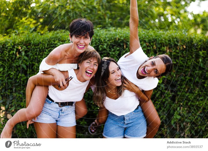 Company of cheerful women having fun in city piggyback friendship laugh humor bonding summer weekend together street delight girlfriend company glad style relax