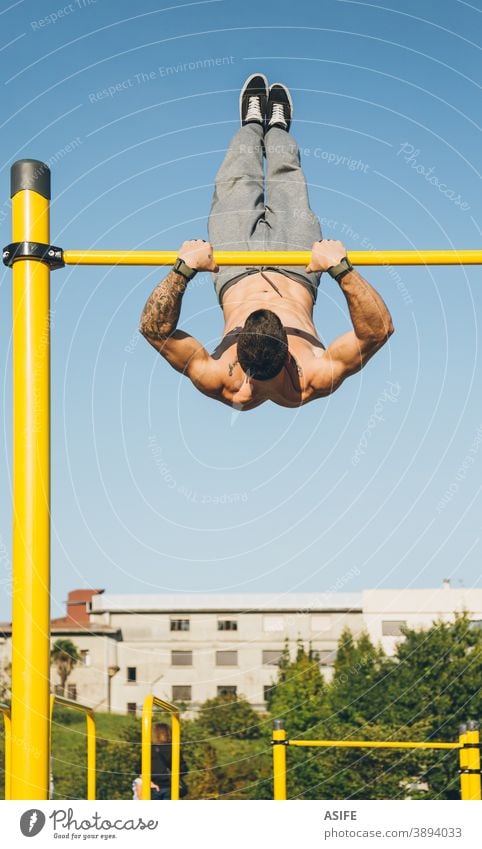 Young athletic man doing gymnastics on bars at a calisthenics park sport athlete muscles strength street freestyle pirouette twirl trick jump body shirtless