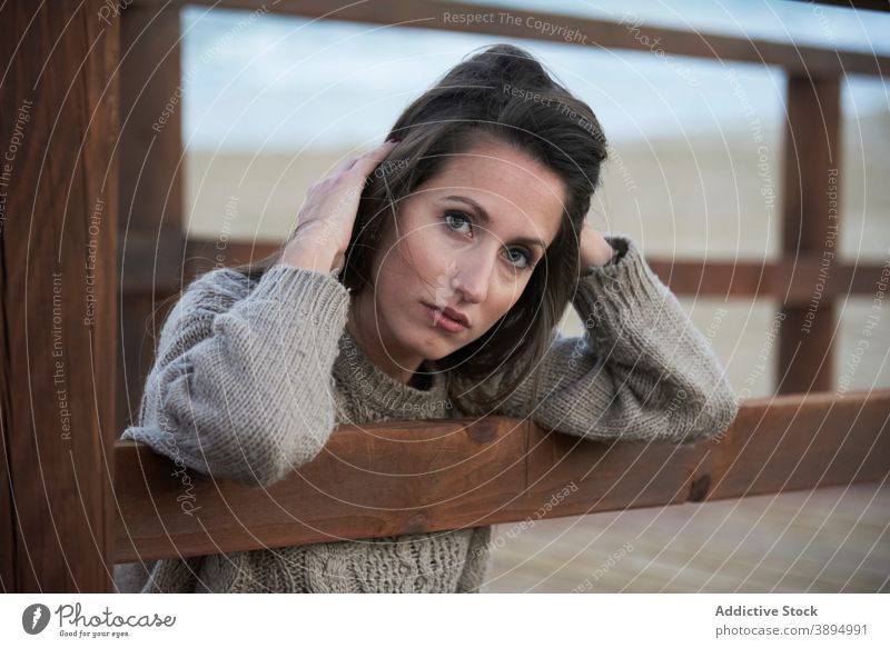 Tender woman on boardwalk on beach sweater fence promenade calm serene alone beautiful recreation lean on casual rest tranquil style charming leisure female
