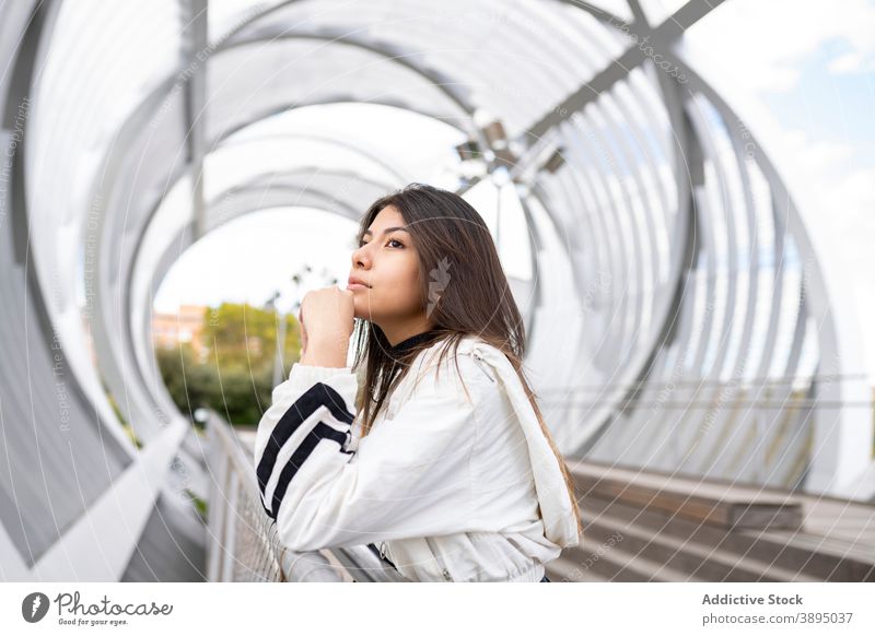 Pensive woman standing on footbridge pensive contemplate thoughtful lonely dream young ponder wistful latin ethnic hispanic female trendy modern style lifestyle