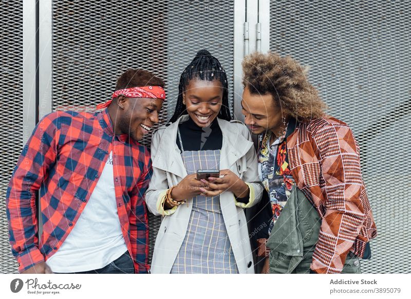 Group of ethnic young friends using smartphones on street browsing mobile phone modern trendy gadget surfing device millennial african american black addict