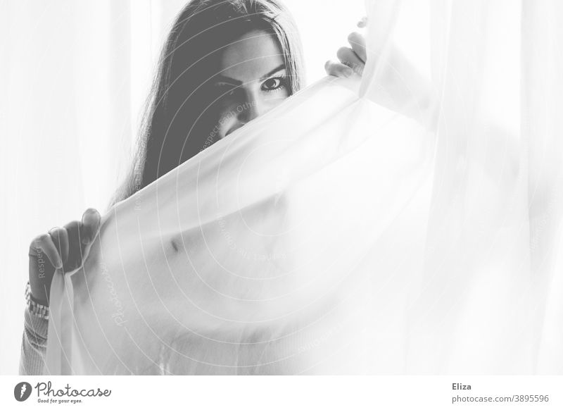 Portrait of a woman looking out behind a white curtain in black and white Woman portrait white fabric Lascivious eyes Looking Black & white photo pretty Event