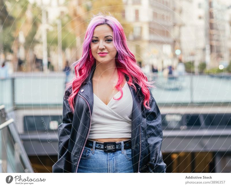 Young woman with dyed hair standing on street pink hair positive alternative millennial urban leather jacket style trendy confident female optimist smile young
