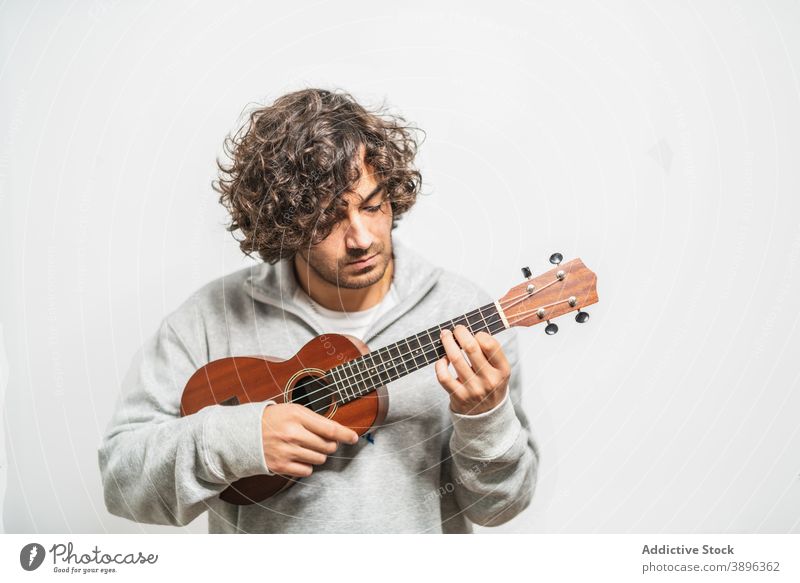 Cheerful man playing ukulele guitar cheerful musician perform positive instrument happy young ethnic hispanic male melody lifestyle song sound acoustic