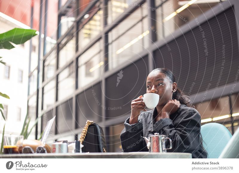 Black woman enjoying weekend in cafe drink tea relax beverage cafeteria content female ethnic black african american table rest cheerful sit casual smile