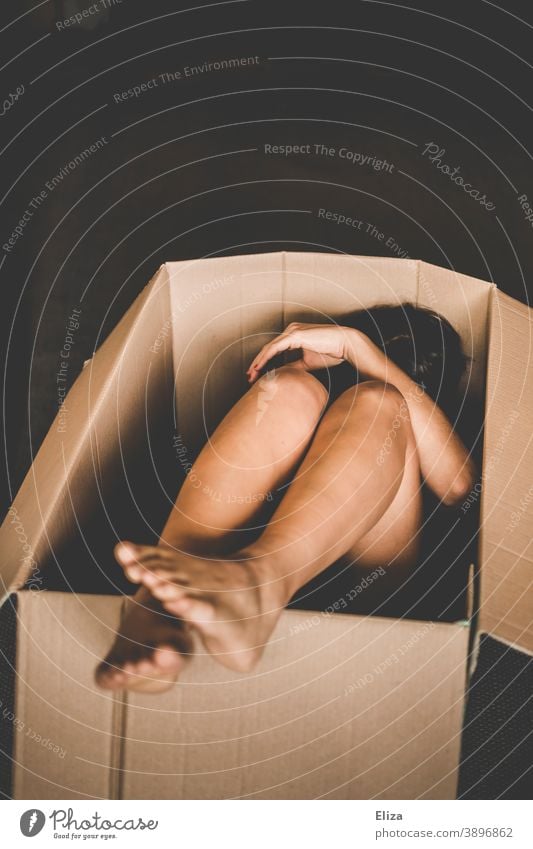 A naked woman huddled in a box Cardboard Naked moving crate Shipping carton Human trafficking Goods Human Package Defenseless huddled together Packaging
