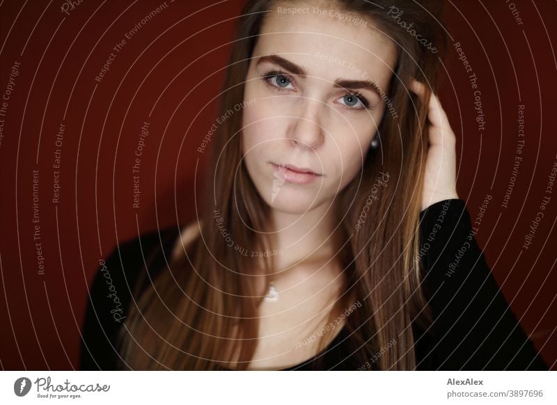 Portrait of a young woman in a room with red wall Student daintily Jewellery Facial expression empathy Looking into the camera Copy Space left Close-up Emotions