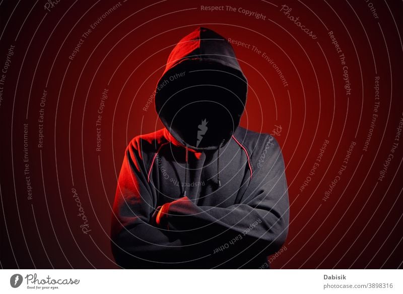 Silhouette af man without face in hood on red background. Anonymous crime concept unknown anonymous hide criminal mystery silhouette invisible stalker black